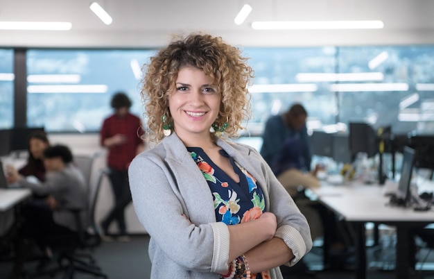 portrait d'une jeune femme développeur de logiciels au bureau de démarrage occupé avec son équipe commerciale multiethnique en arrière-plan