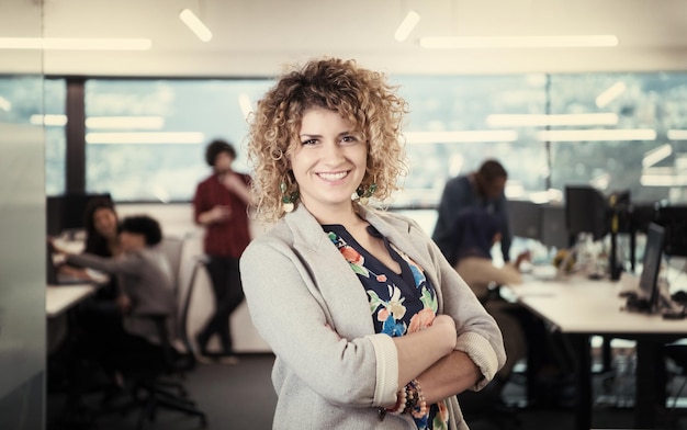 portrait d'une jeune femme développeur de logiciels au bureau de démarrage occupé avec son équipe commerciale multiethnique en arrière-plan