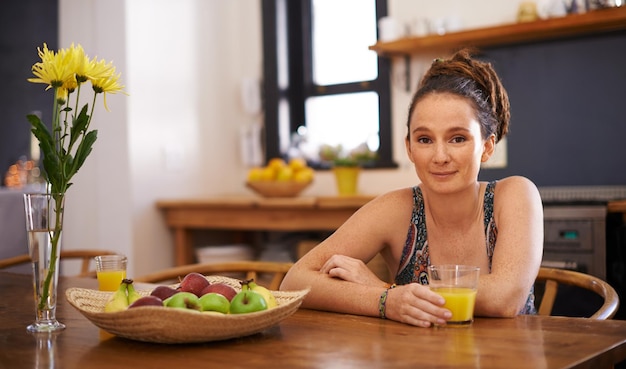 Portrait d'une jeune femme avec des dreadlocks assis à une table avec un verre de jus d'orange