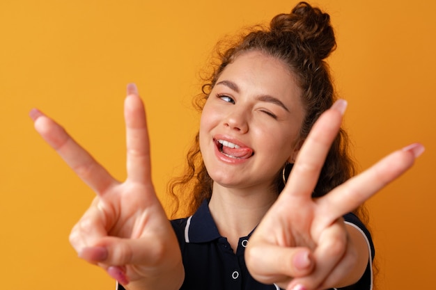 Photo portrait d'une jeune femme drôle montrant un geste de paix sur fond jaune