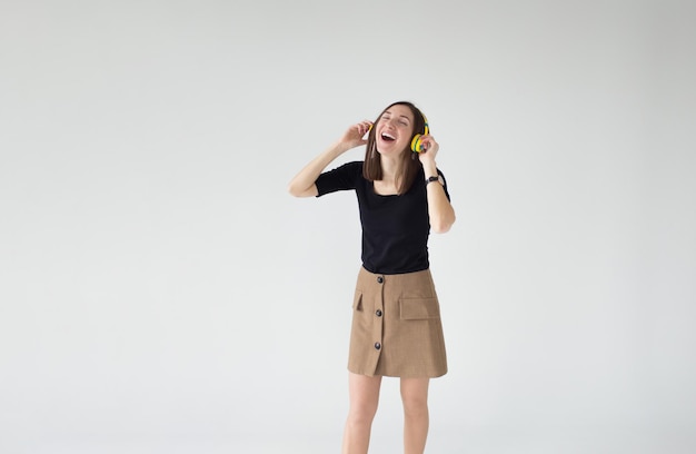 Portrait d'une jeune femme écoutant de la musique avec un casque jaune sur fond blanc isolé