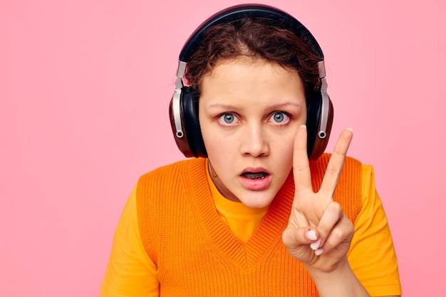 Portrait d'une jeune femme écoutant de la musique avec des écouteurs chandail orange émotions fun arrière-plans isolés inchangés