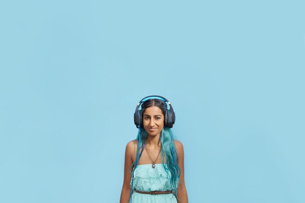 Photo portrait d'une jeune femme écoutant de la musique sur un fond bleu