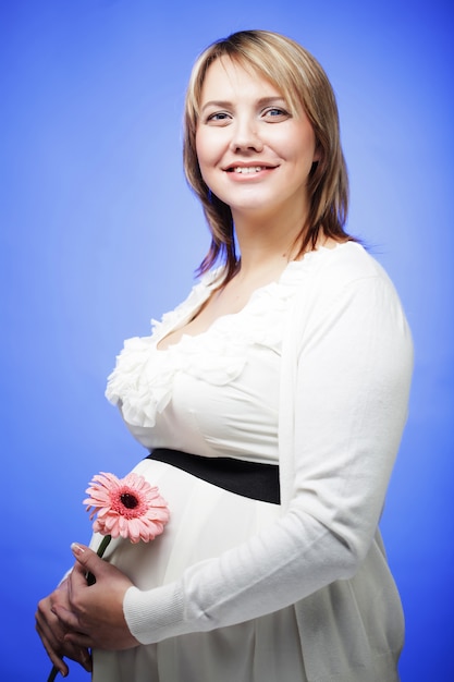 Portrait de la jeune femme enceinte souriante heureuse avec fleur