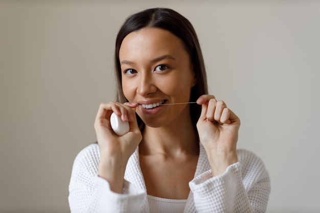 Portrait d'une jeune femme engagée dans des procédures quotidiennes après la douche Se brosser les dents passer la soie dentaire Sourire de Blanche-Neige clin d'œil avec ses yeux Soins beauté et santé