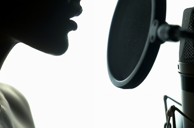 Photo portrait de jeune femme enregistrant une chanson dans un studio professionnel.