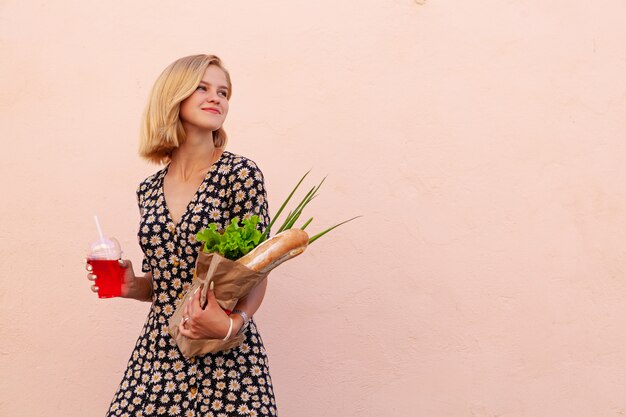 Portrait de jeune femme étudiante souriante avec sac de boutique d'artisanat, avec salade verte, oignon et pain. Nourriture saine, collation