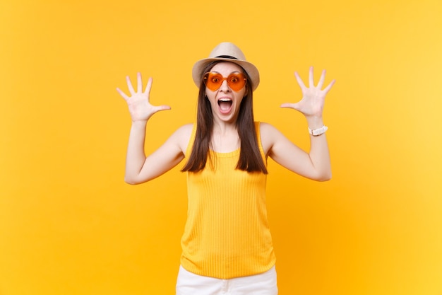 Portrait d'une jeune femme excitée qui crie dans des verres oranges écartant les mains, gardant la bouche grande ouverte, l'air surpris isolé sur fond jaune. Concept d'émotions sincères de personnes. Espace publicitaire