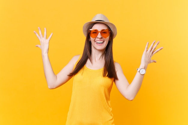 Portrait d'une jeune femme excitée qui crie dans des verres oranges écartant les mains, gardant la bouche grande ouverte, l'air surpris isolé sur fond jaune. Concept d'émotions sincères de personnes. Espace publicitaire