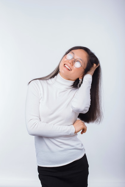 Portrait d'une jeune femme excitée touche ses cheveux sur blanc.