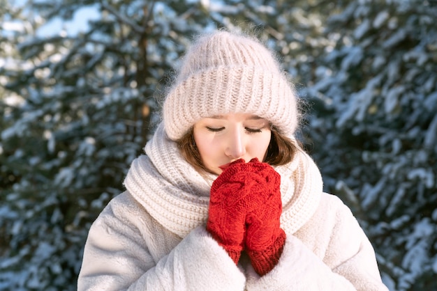 Portrait de jeune femme à l'extérieur en hiver. Bonnet et gants tricotés.