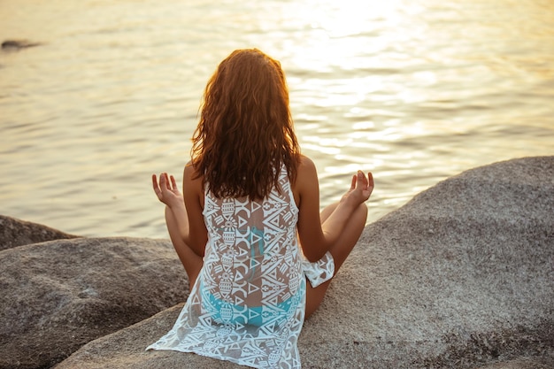 Portrait d'une jeune femme faisant du yoga tôt le matin au bord de l'océan