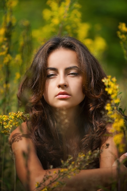 Photo portrait d'une jeune femme sur fond de champ de fleurs estompé