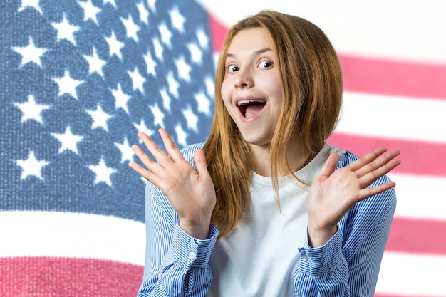 Portrait d'une jeune femme sur le fond du drapeau des États-Unis Concept de patriotisme Une fille émotive