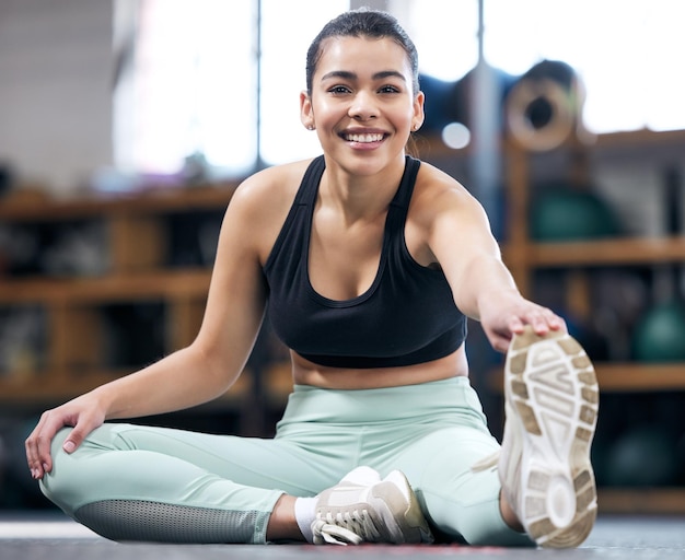 Portrait d'une jeune femme en forme qui s'étend dans une salle de sport