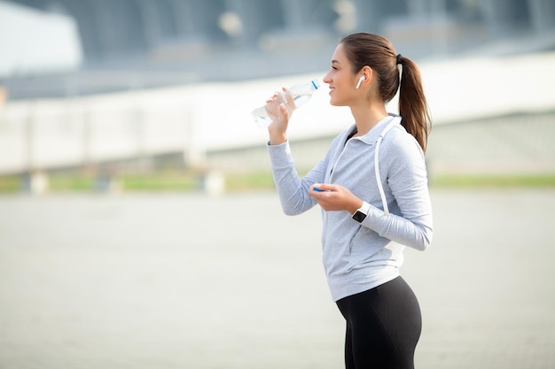 Portrait d'une jeune femme en forme tenant une bouteille d'eau