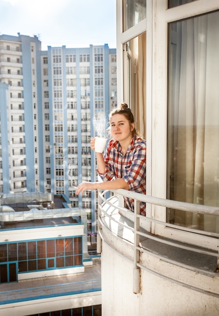 Photo portrait de jeune femme fumant et buvant du café sur le balcon