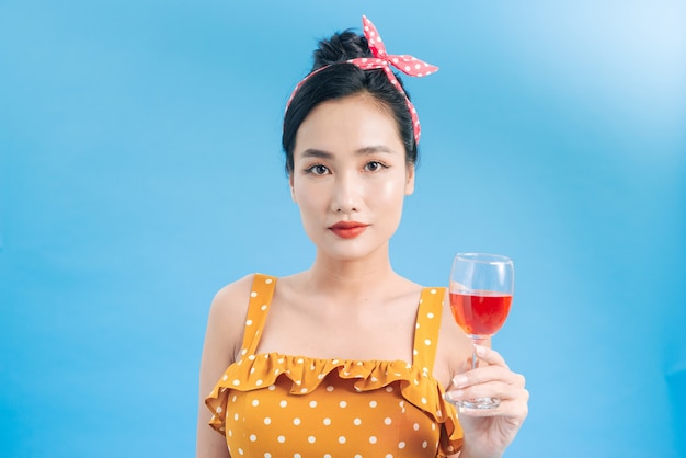 Portrait d'une jeune femme gaie en robe tenant une coupe de champagne isolée sur bleu