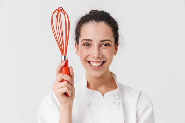 Portrait d'une jeune femme gaie avec des ustensiles de cuisine