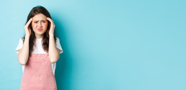 Portrait de jeune femme grimaçant de migraine douloureuse fronçant les sourcils et touchant la tête ayant des maux de tête s