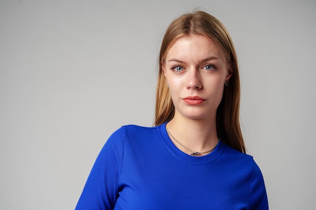 Portrait d'une jeune femme en haut bleu sur fond gris