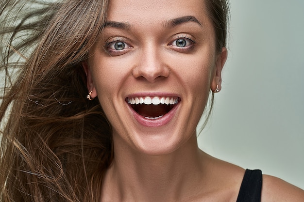 Portrait de jeune femme heureuse brune caucasienne avec excité étonné surpris joyeux étonné expression de visage choqué excité avec la bouche ouverte de surprise. Wow et omg