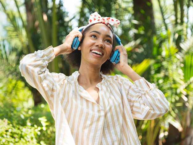 Portrait jeune femme heureuse avec un casque dans le jardin