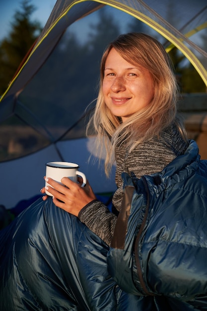 Portrait de jeune femme heureuse dans un sac de couchage à l'extérieur