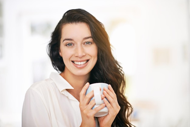 Portrait d'une jeune femme heureuse en dégustant une tasse de café