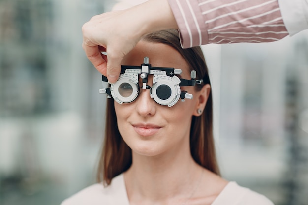 Portrait de jeune femme heureuse lors de l'examen de la vue chez l'optométriste opticien