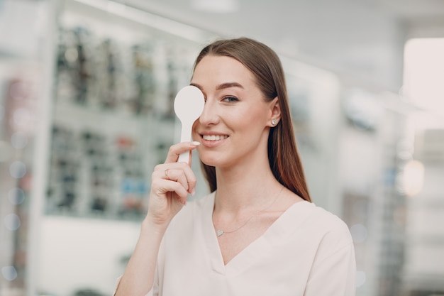 Portrait de jeune femme heureuse lors de l'examen de la vue chez l'optométriste opticien