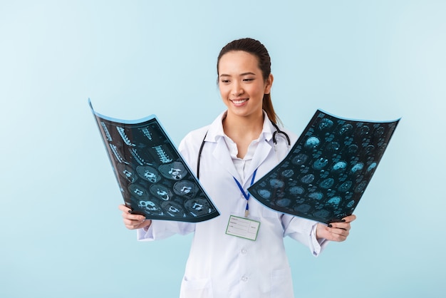 portrait d'une jeune femme heureuse médecin posant isolé sur un mur bleu avec des rayons x.