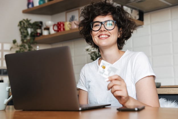 Portrait D'une Jeune Femme Heureuse Portant Des Lunettes Travaillant Sur Un Ordinateur Portable à La Maison Le Matin