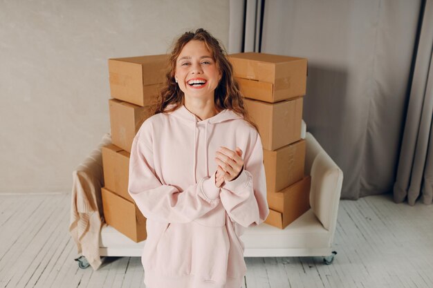 Portrait d'une jeune femme heureuse qui déménage avec des boîtes de carton dans un nouvel appartement.