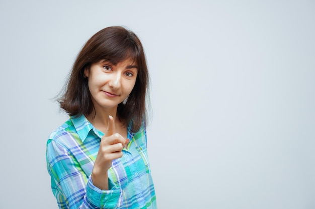 Portrait de jeune femme heureuse de race blanche, pointant le doigt sur la caméra isolée sur fond gris