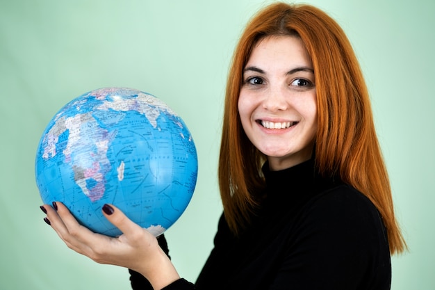 Portrait d'une jeune femme heureuse tenant le globe géographique du monde dans ses mains