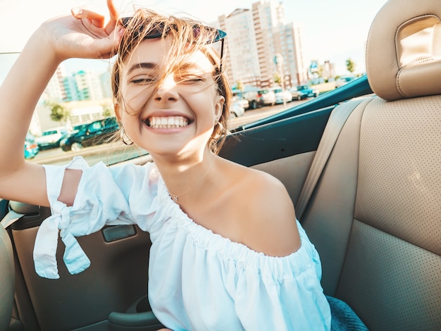 Portrait de jeune femme hipster belle et souriante en voiture décapotable