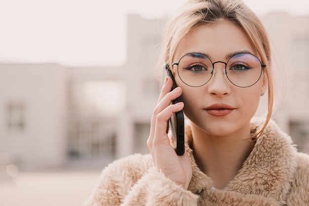 Portrait de jeune femme hipster portant des lunettes et parlant au téléphone