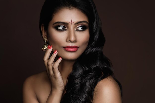 Portrait de jeune femme indienne avec beau maquillage et coiffure sur fond marron