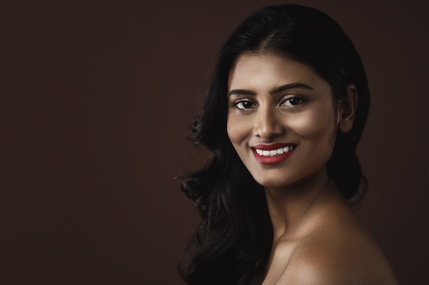 Portrait de jeune femme indienne avec beau maquillage et coiffure sur mur marron