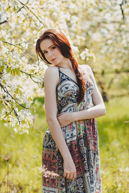 Portrait de jeune femme insouciante en robe de style bohème au printemps jardin de fleurs de cerisier.