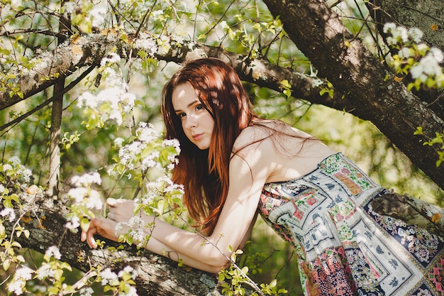 Portrait de jeune femme insouciante en robe de style bohème au printemps jardin de fleurs de cerisier.