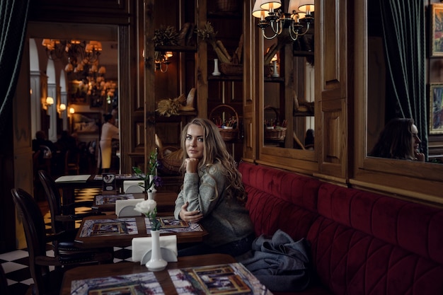 Portrait d'une jeune femme à l'intérieur du restaurant à la table en souriant à la caméra