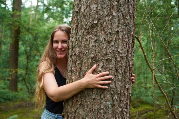 Un portrait d'une jeune femme italienne serrant un arbre dans une forêt