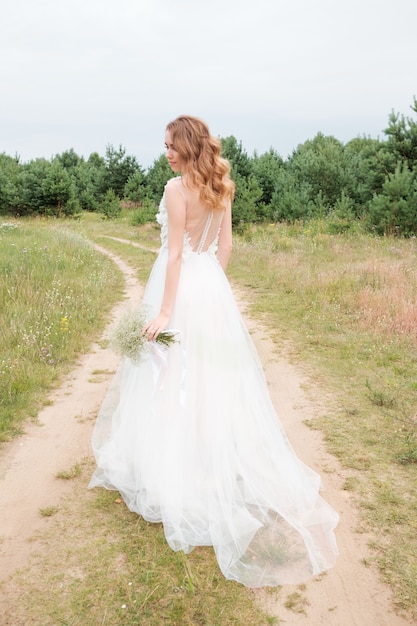 Portrait de jeune femme jolie en robe de mariée blanche à l'extérieur