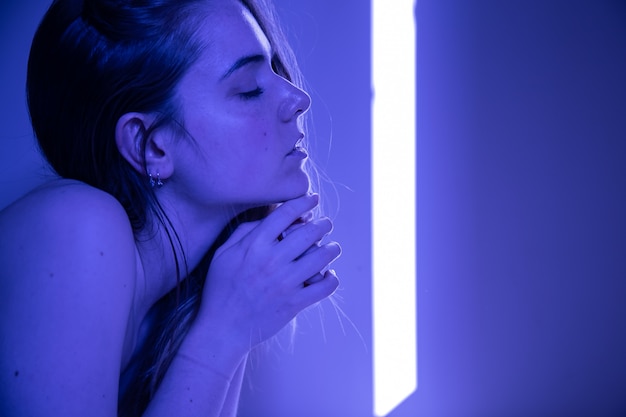 Portrait de jeune femme jolie solitaire aux cheveux bruns, allongée sur le lit avec les yeux fermés