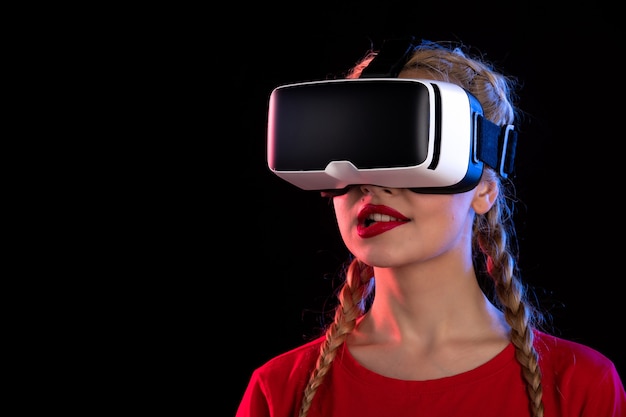 Portrait de jeune femme jouant à la réalité virtuelle sur le mur sombre