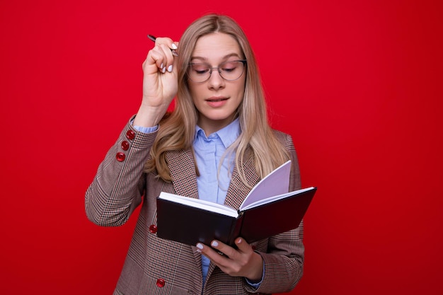 Portrait d'une jeune femme avec un journal et un stylo sur fond rouge