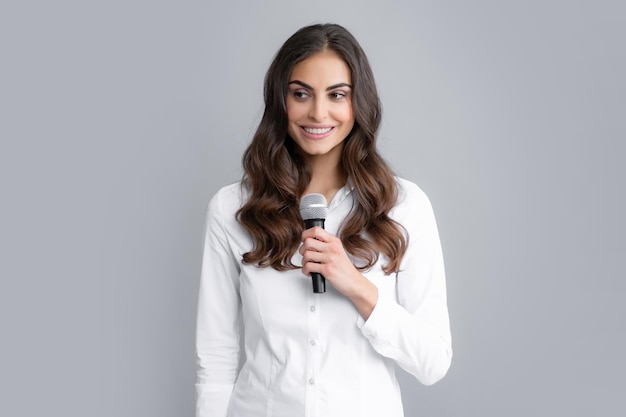 Portrait de jeune femme journaliste en chemise décontractée tenant un microphone posant des questions discutant des problèmes d'interview isolé sur fond gris
