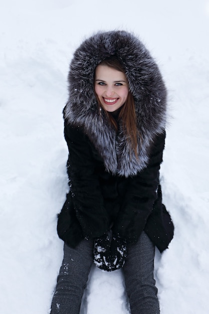 Portrait d'une jeune femme joyeuse assise sur la neige